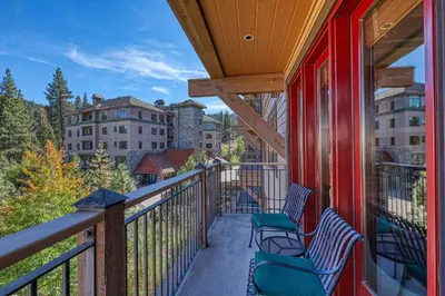 a balcony with two chairs and a view at Catamount Lodge 301 by East West Hospitality in Truckee