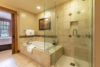 a bathroom with a tub and a glass shower at Catamount Lodge 312 by East West Hospitality in Truckee