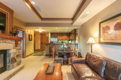 a living room with a leather couch and a fireplace at Catamount Lodge 312 by East West Hospitality in Truckee