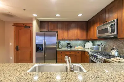a kitchen with wooden cabinets and a stainless steel refrigerator at Catamount Lodge 312 by East West Hospitality in Truckee