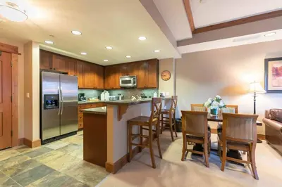 a kitchen with a table and a kitchen with a refrigerator at Catamount Lodge 312 by East West Hospitality in Truckee