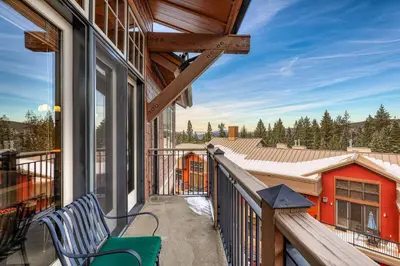 a balcony of a house with a bench on it at Catamount Lodge 401 by East West Hospitality in Truckee