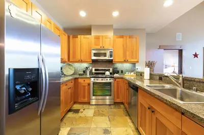 a kitchen with wooden cabinets and a stainless steel refrigerator at Catamount Lodge 401B by East West Hospitality in Truckee