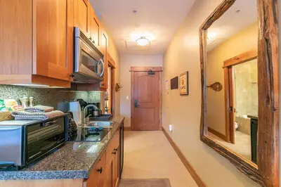 a kitchen with wooden cabinets and a sink and a mirror at Catamount Lodge 401A by East West Hospitality in Truckee