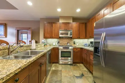 a kitchen with wooden cabinets and stainless steel appliances at Catamount Lodge 404 by East West Hospitality in Truckee