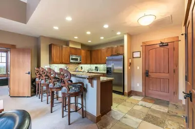 a kitchen with wooden cabinets and bar stools at Catamount Lodge 404 by East West Hospitality in Truckee