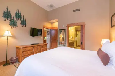 a bedroom with a large white bed and a television at Catamount Lodge 404B by East West Hospitality in Truckee