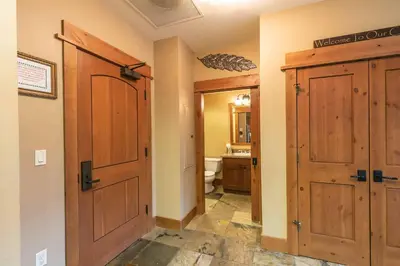 a bathroom with a wooden door and a toilet at Catamount Lodge 404B by East West Hospitality in Truckee