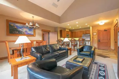 a living room with leather furniture and a kitchen at Catamount Lodge 404B by East West Hospitality in Truckee