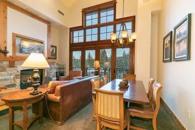 a living room with a table and a couch and a fireplace at Catamount Lodge 405 by East West Hospitality in Truckee