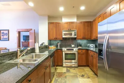 a kitchen with wooden cabinets and a stainless steel refrigerator at Catamount Lodge 405 by East West Hospitality in Truckee