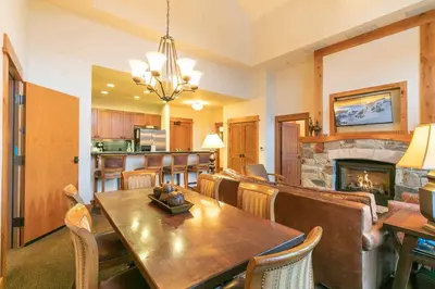 a dining room with a table and a fireplace at Catamount Lodge 405 by East West Hospitality in Truckee