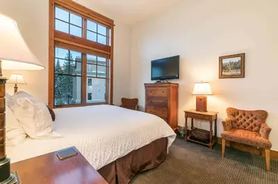 a bedroom with a bed and a tv and a chair at Catamount Lodge 405A by East West Hospitality in Truckee