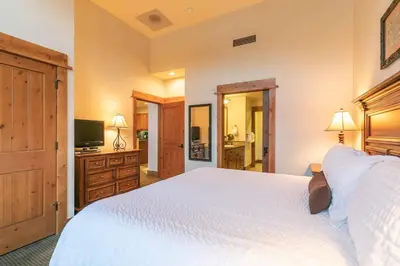 a bedroom with a large white bed and a television at Catamount Lodge 405B by East West Hospitality in Truckee