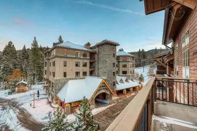 a view of a resort in the snow from a balcony at Catamount Lodge 405B by East West Hospitality in Truckee