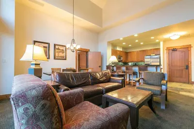 a living room with couches and a table and a kitchen at Catamount Lodge 405B by East West Hospitality in Truckee