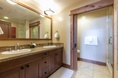 a bathroom with two sinks and a large mirror at Catamount Lodge 408 by East West Hospitality in Truckee