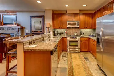 a large kitchen with wooden cabinets and stainless steel appliances at Catamount Lodge 411 by East West Hospitality in Truckee