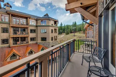 a balcony with a chair and some buildings at Catamount Lodge 411 by East West Hospitality in Truckee