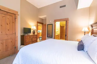 a bedroom with a large white bed and a television at Catamount Lodge 409 by East West Hospitality in Truckee