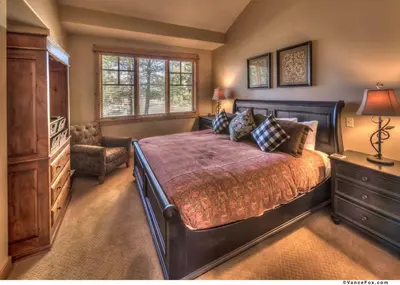 a bedroom with a large bed with a dresser and a chair at Fairway Drive 13136 by East West Hospitality in Truckee