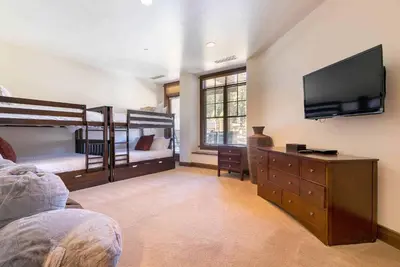 a bedroom with two bunk beds and a flat screen tv at Great Bear Lodge 206 by East West Hospitality in Truckee