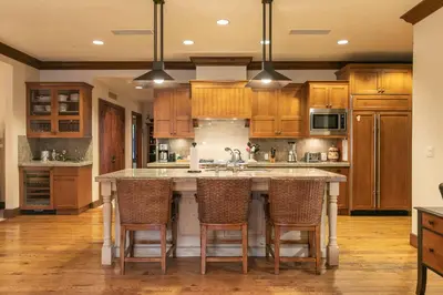 a kitchen with wooden cabinets and a large island with bar chairs at Great Bear Lodge 201 by East West Hospitality in Truckee