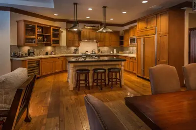 a large kitchen with wooden cabinets and bar stools at Great Bear Lodge 306 by East West Hospitality in Truckee
