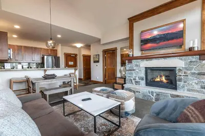 a living room with a fireplace and a kitchen at Iron Horse Lodge North 309 by East West Hospitality in Truckee