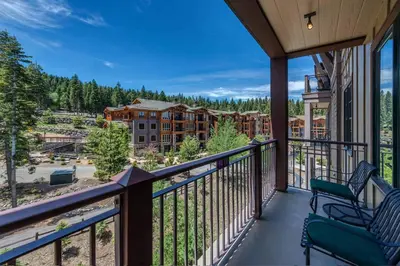a balcony with two chairs and a view of a resort at Iron Horse Lodge South 406 by East West Hospitality in Truckee