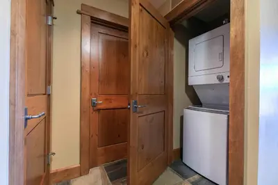 a bathroom with a wooden door and a washer and dryer at Iron Horse Lodge South 305 by East West Hospitality in Truckee