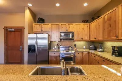 a kitchen with wooden cabinets and a stainless steel refrigerator at Iron Horse Lodge North 107 by East West Hospitality in Truckee