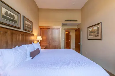 a bedroom with a large bed with white sheets at Iron Horse Lodge North 107 by East West Hospitality in Truckee