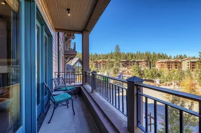 a balcony with two chairs and a view of condos at Iron Horse Lodge North 205 by East West Hospitality in Truckee