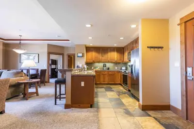 a kitchen with wooden cabinets and a living room at Iron Horse Lodge North 205 by East West Hospitality in Truckee