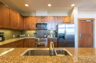 a kitchen with wooden cabinets and a stainless steel refrigerator at Iron Horse Lodge North 305 by East West Hospitality in Truckee
