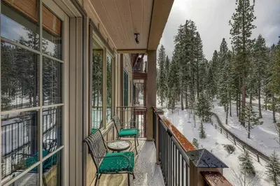 a balcony with chairs and a table and snow covered trees at Iron Horse Lodge South 404 by East West Hospitality in Truckee