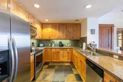 a kitchen with wooden cabinets and a stainless steel refrigerator at Iron Horse Lodge North 207 by East West Hospitality in Truckee