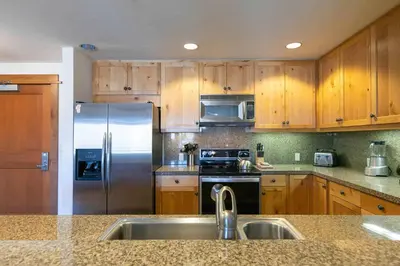 a kitchen with wooden cabinets and a stainless steel refrigerator at Iron Horse Lodge North 207 by East West Hospitality in Truckee