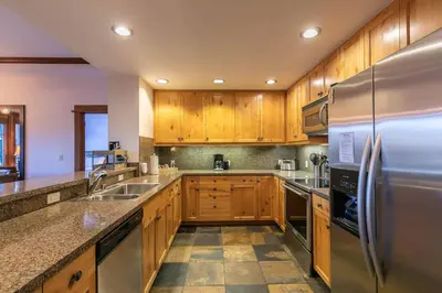 a kitchen with wooden cabinets and a stainless steel refrigerator at Iron Horse Lodge South 209 by East West Hospitality in Truckee