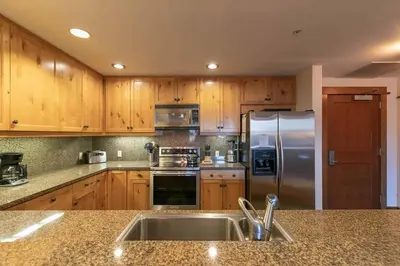 a kitchen with wooden cabinets and a stainless steel refrigerator at Iron Horse Lodge South 209 by East West Hospitality in Truckee