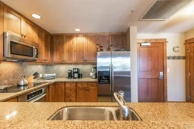 a kitchen with wooden cabinets and a stainless steel refrigerator at Iron Horse Lodge South 401 by East West Hospitality in Truckee