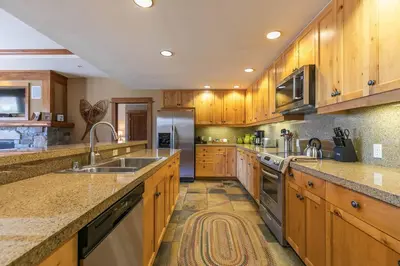 a large kitchen with wooden cabinets and stainless steel appliances at Iron Horse Lodge North 201 by East West Hospitality in Truckee