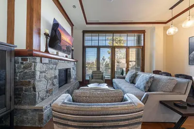 a living room with a couch and a stone fireplace at Iron Horse Lodge North 103 by East West Hospitality in Truckee