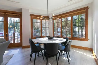 a dining room with a table and chairs and windows at Iron Horse Lodge South 308 by East West Hospitality in Truckee