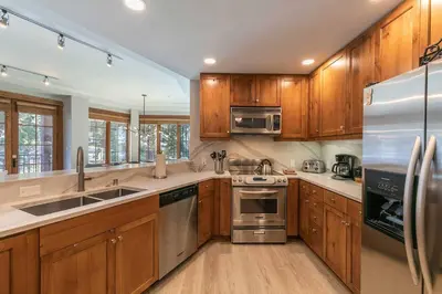 a kitchen with wooden cabinets and stainless steel appliances at Iron Horse Lodge South 308 by East West Hospitality in Truckee