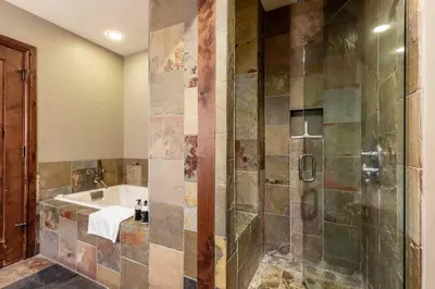 a bathroom with a tub and a shower stall at One Village Place 508 by East West Hospitality in Truckee