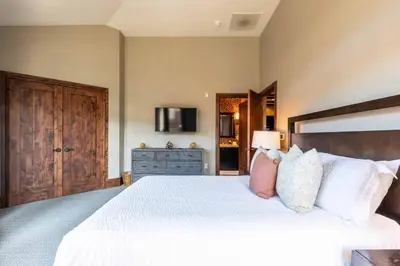 a bedroom with a large bed with white sheets and pillows at One Village Place 508 by East West Hospitality in Truckee