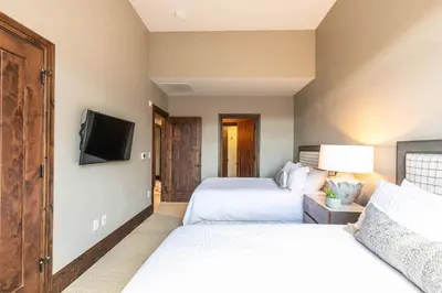 a bedroom with two beds and a flat screen tv at One Village Place 502 by East West Hospitality in Truckee