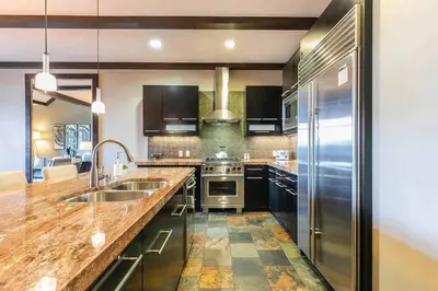 a large kitchen with a sink and a refrigerator at One Village Place 502 by East West Hospitality in Truckee